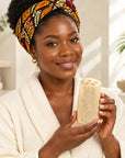 Ugandan African woman holding the Glow Loofah in a bright, editorial spa setting